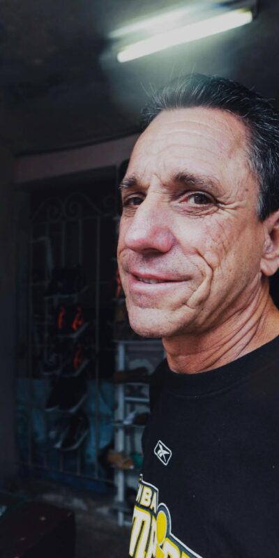 Elderly man smiling indoors at a shoe store with vibrant lighting.