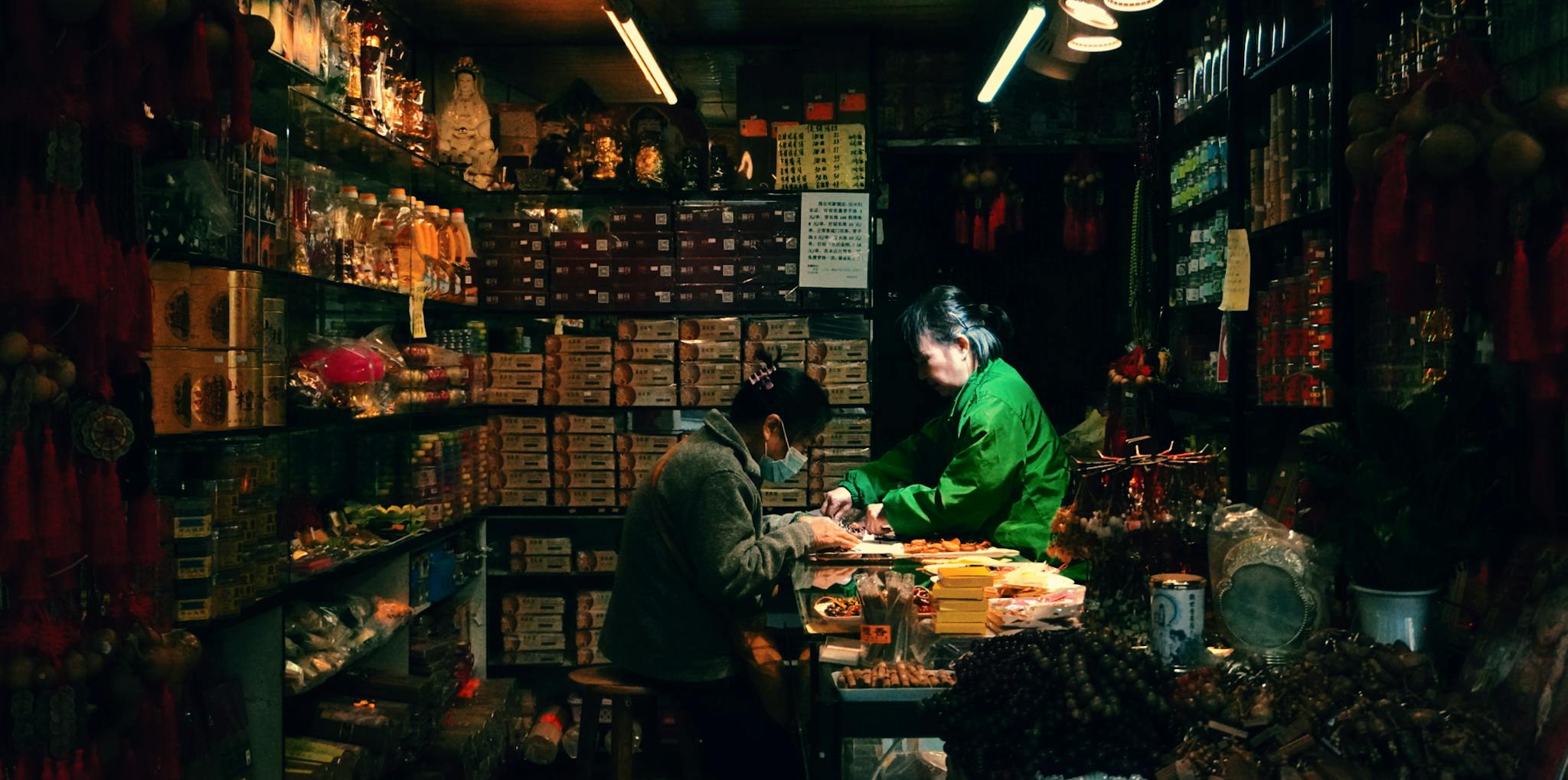 Two people engaged in conversation inside an authentic Asian shop full of traditional items.